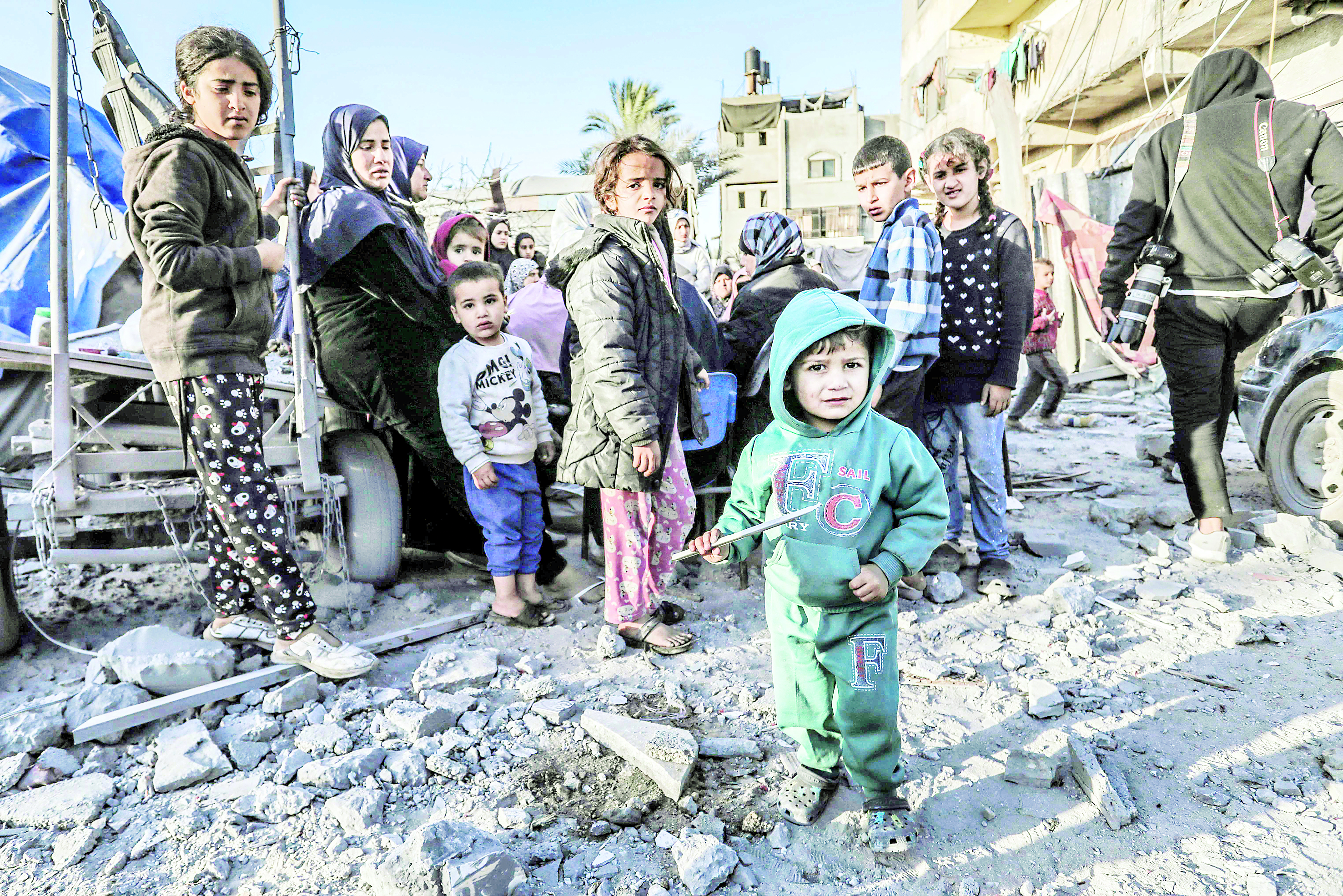  أطفال يقفون وسط موقع غارة إسرائيلية على دير البلح (أ ف ب)