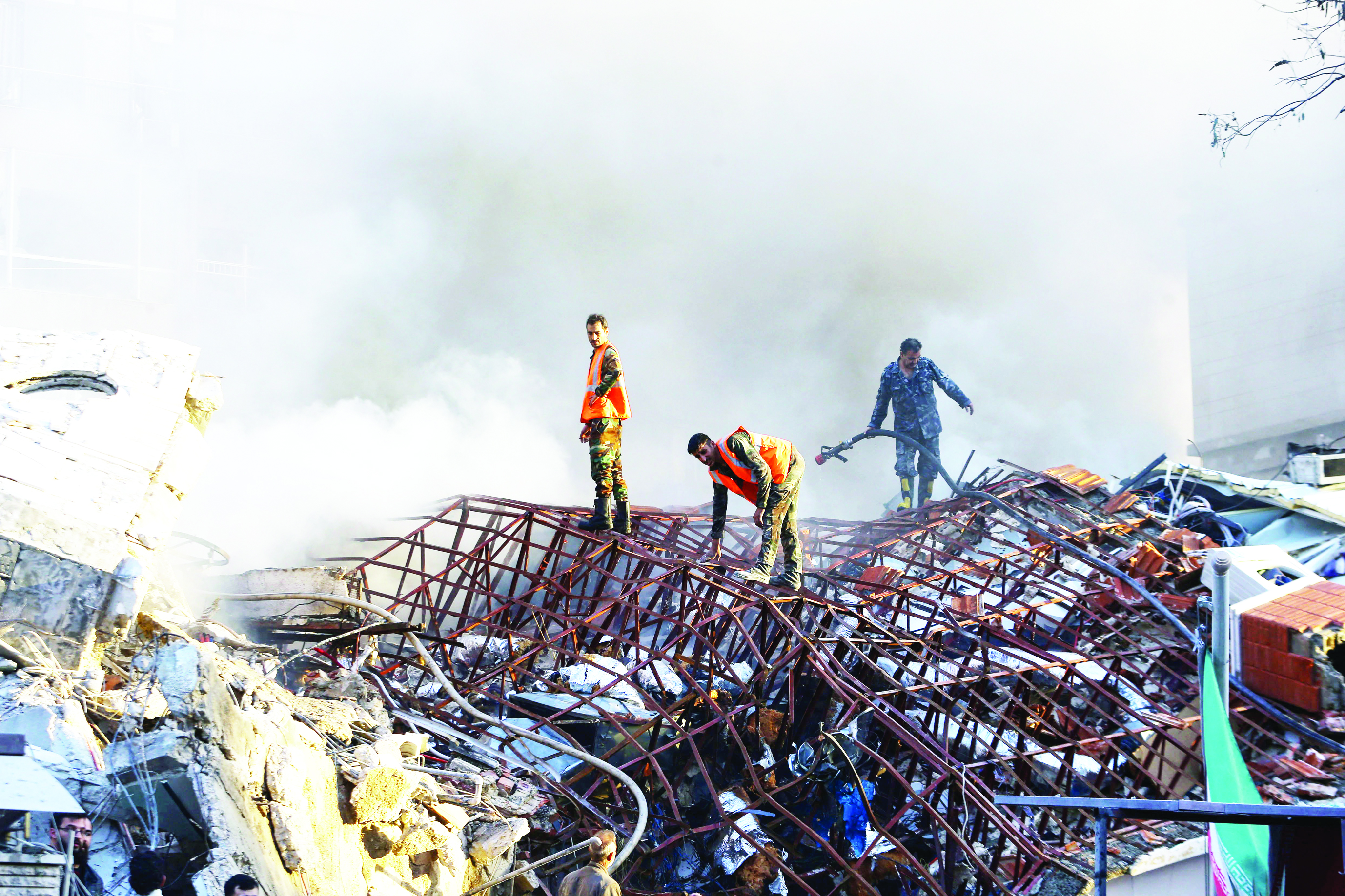 أفراد الطوارئ يخمدون حريقاً في موقع الضربات قرب مبنى مجاور للسفارة الإيرانية في دمشق (أ ف ب)
