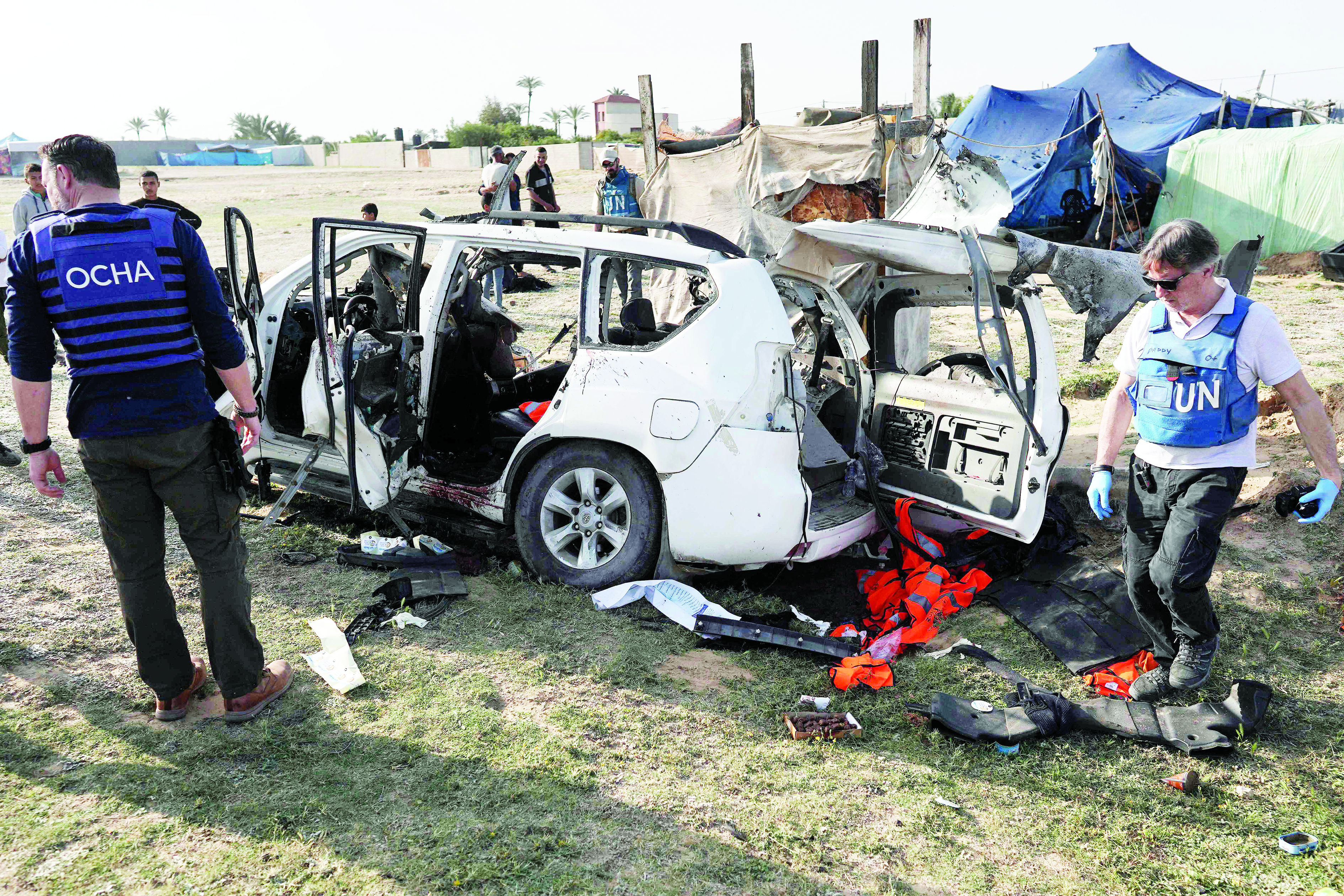 موظفون أمميون يتفقدون سيارة تستخدمها مؤسسة «المطبخ العالمي» بعد تعرضها لأضرار (أ ف ب)