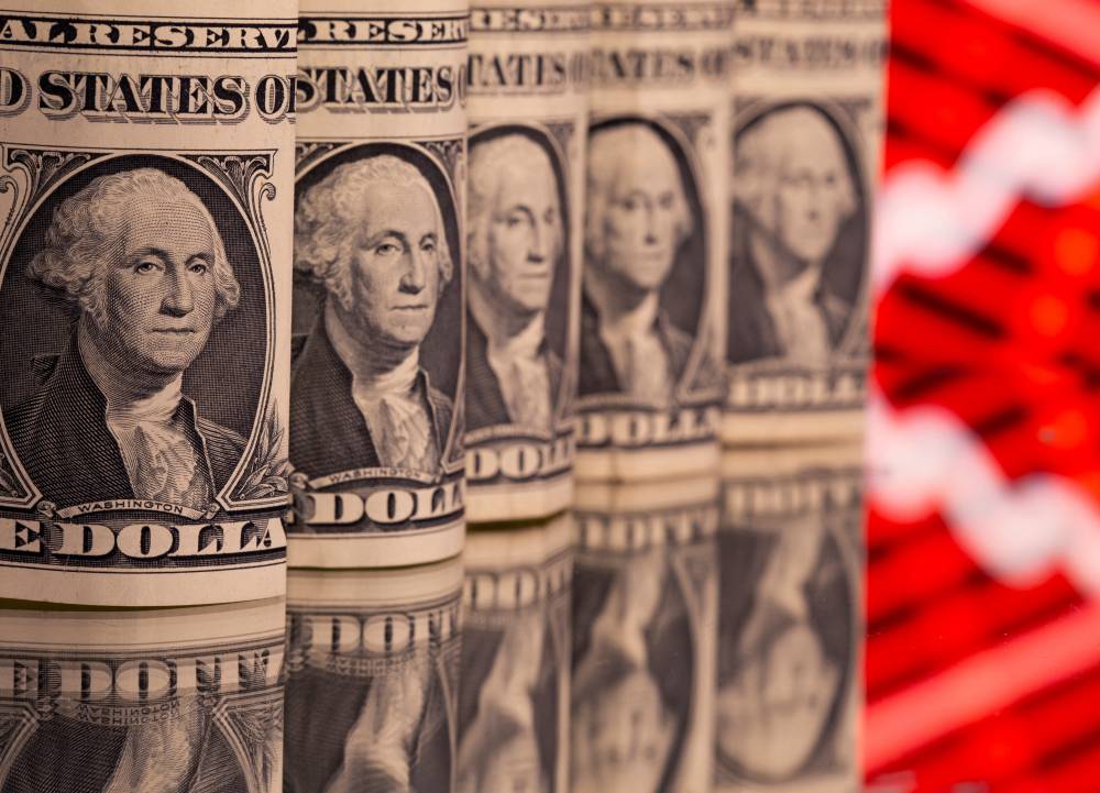 أوراق النقدية بالدولار الأمريكي أمام رسم بياني للأسهم (رويترز)
