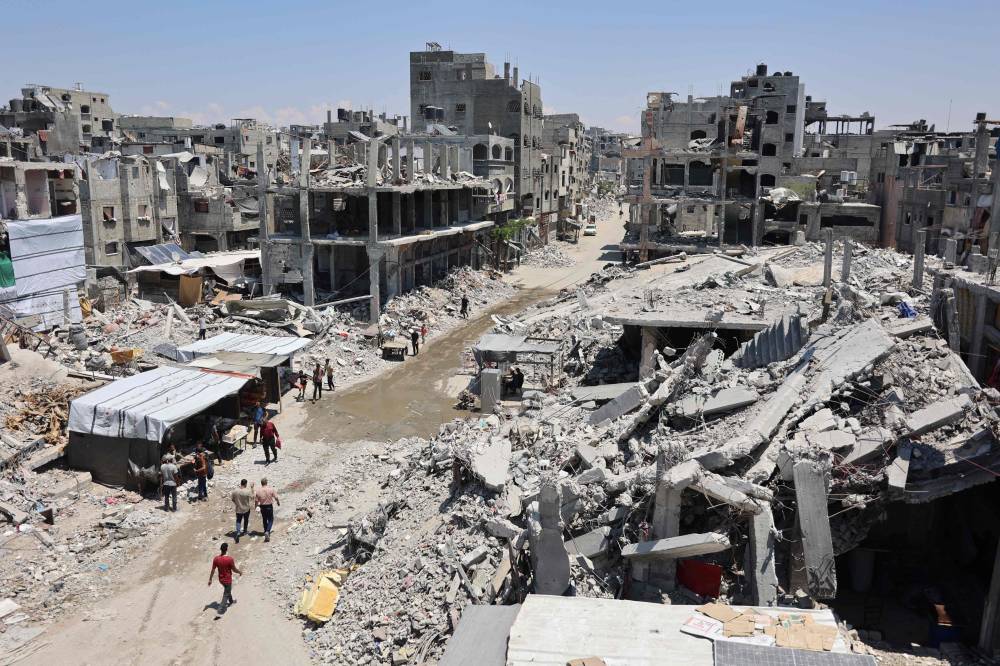 فلسطينيون يسيرون بجوار أنقاض المباني في مخيم جباليا للاجئين (أ ف ب)