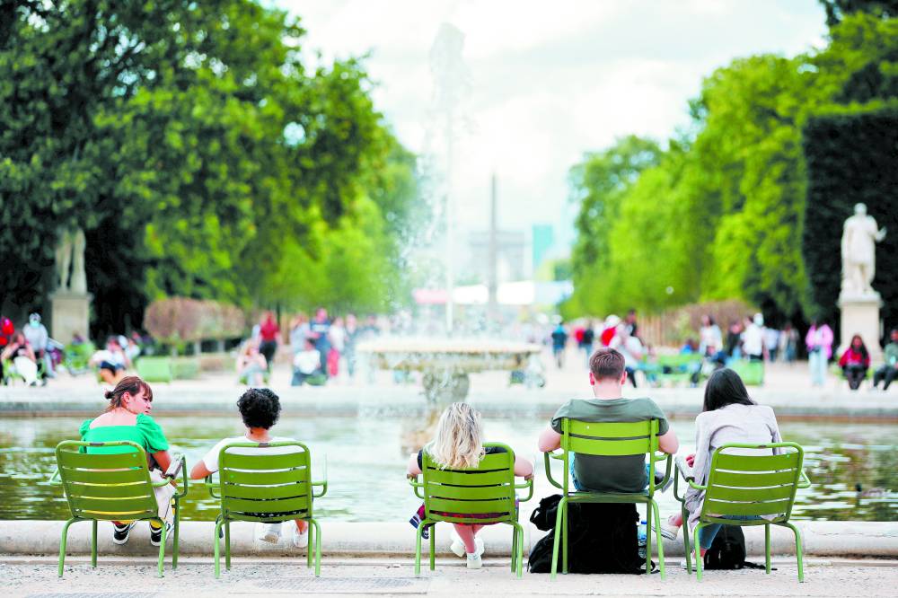 فرنسيون يجلسون حول النافورة في حدائق التويلري في باريس (رويترز)