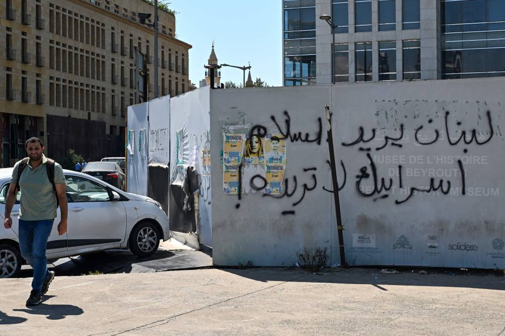 لبناني يمر بجانب شعار "لبنان يريد السلام، وإسرائيل لا تريده"، وسط بيروت 