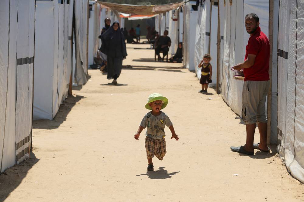 صبي فلسطيني نازح مبتورة ساقه يجري في مخيم في دير البلح (رويترز) 