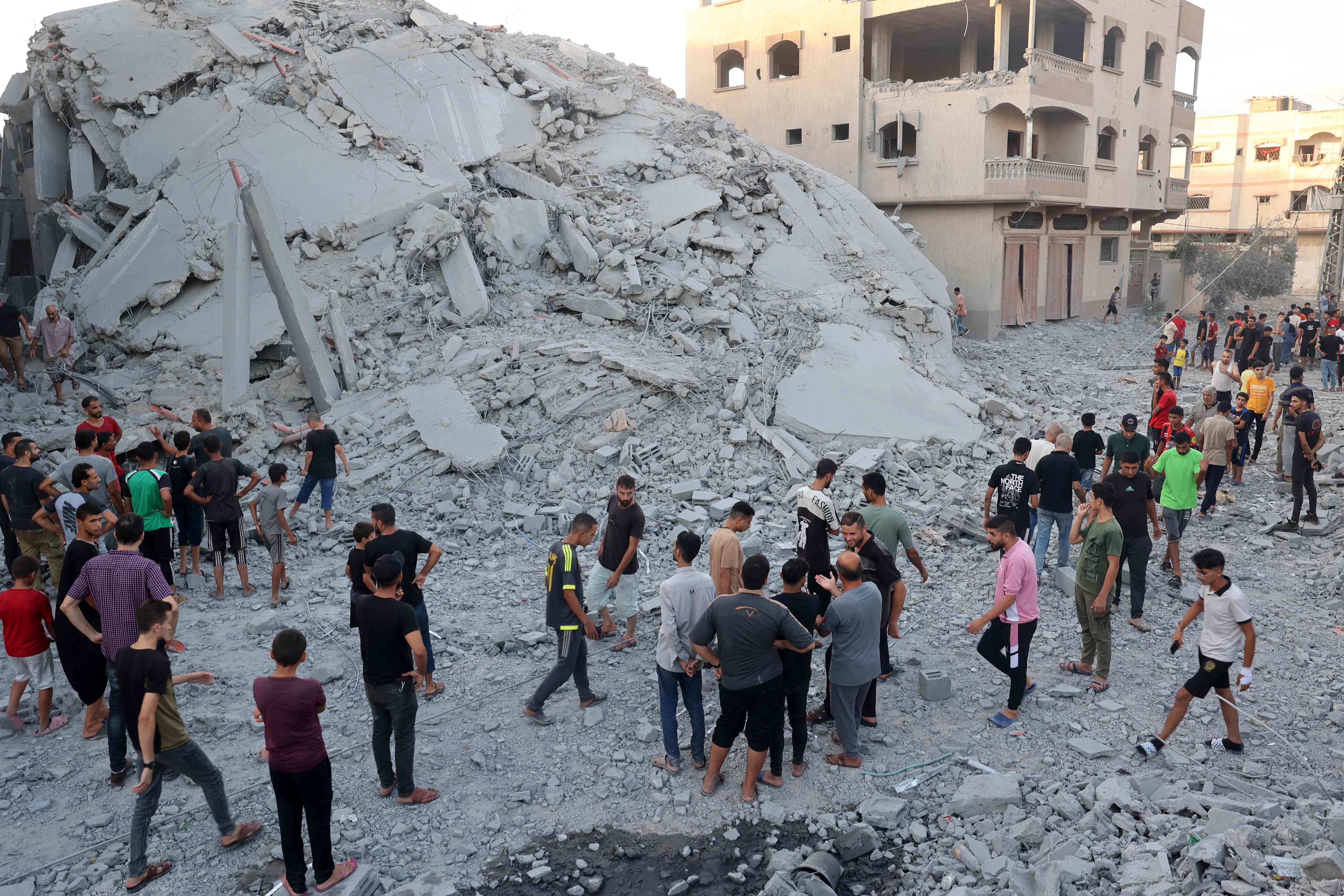 فلسطينيون يتفقدون مبنى بعد قصف إسرائيلي وسط قطاع غزة (أ ف ب)