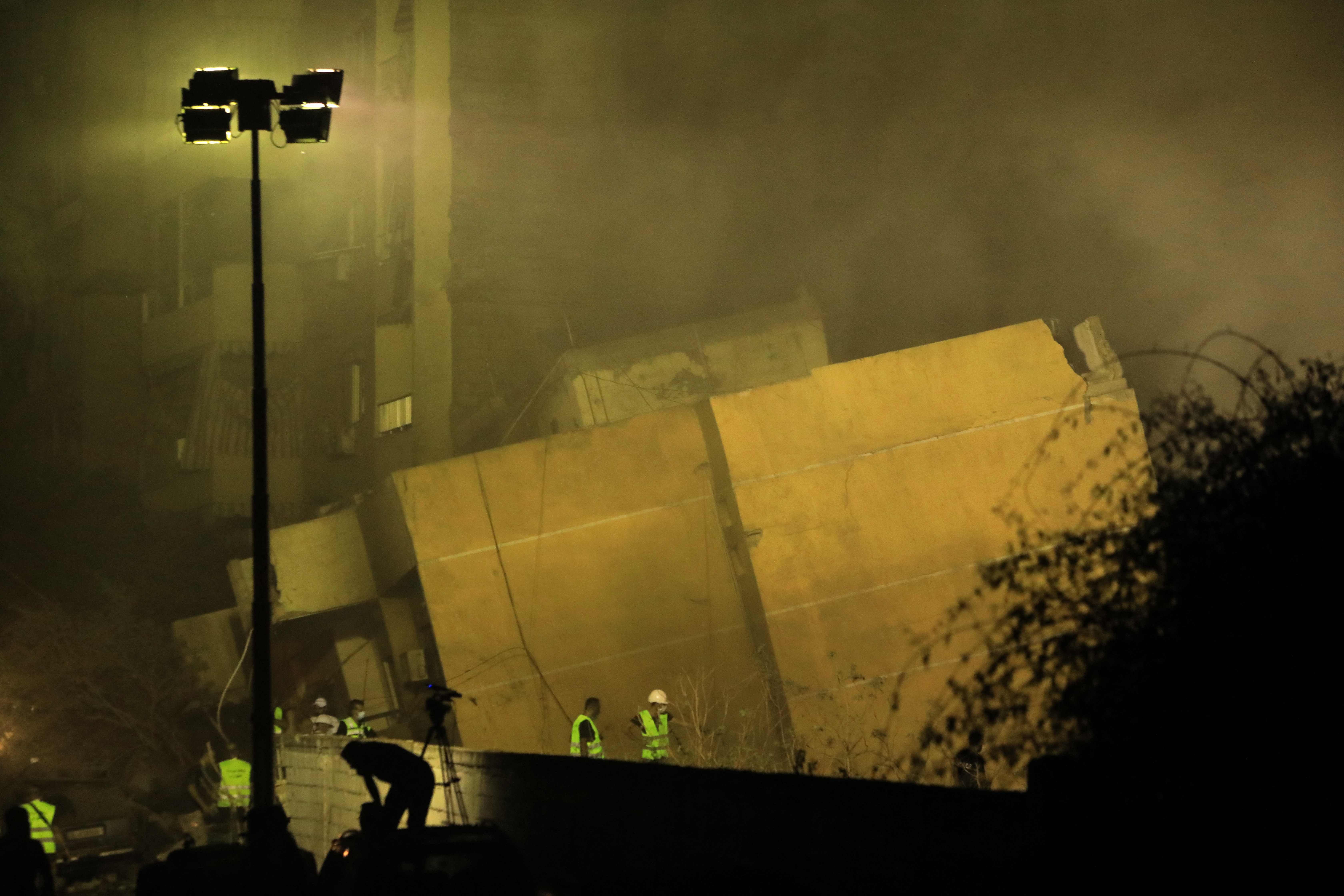 TOPSHOT - Rescuers stand outside a builiding destroyed in an Israeli air strike in the Haret Hreik neighbourhood of Beirut's southern suburbs on September 27, 2024. Israel carried out air strikes on the south of Lebanon's capital Beirut on September 27 that it said targeted Hezbollah's headquarters, moments after Prime Minister Benjamin Netanyahu vowed to keep fighting the militant group. (Photo by AFP)