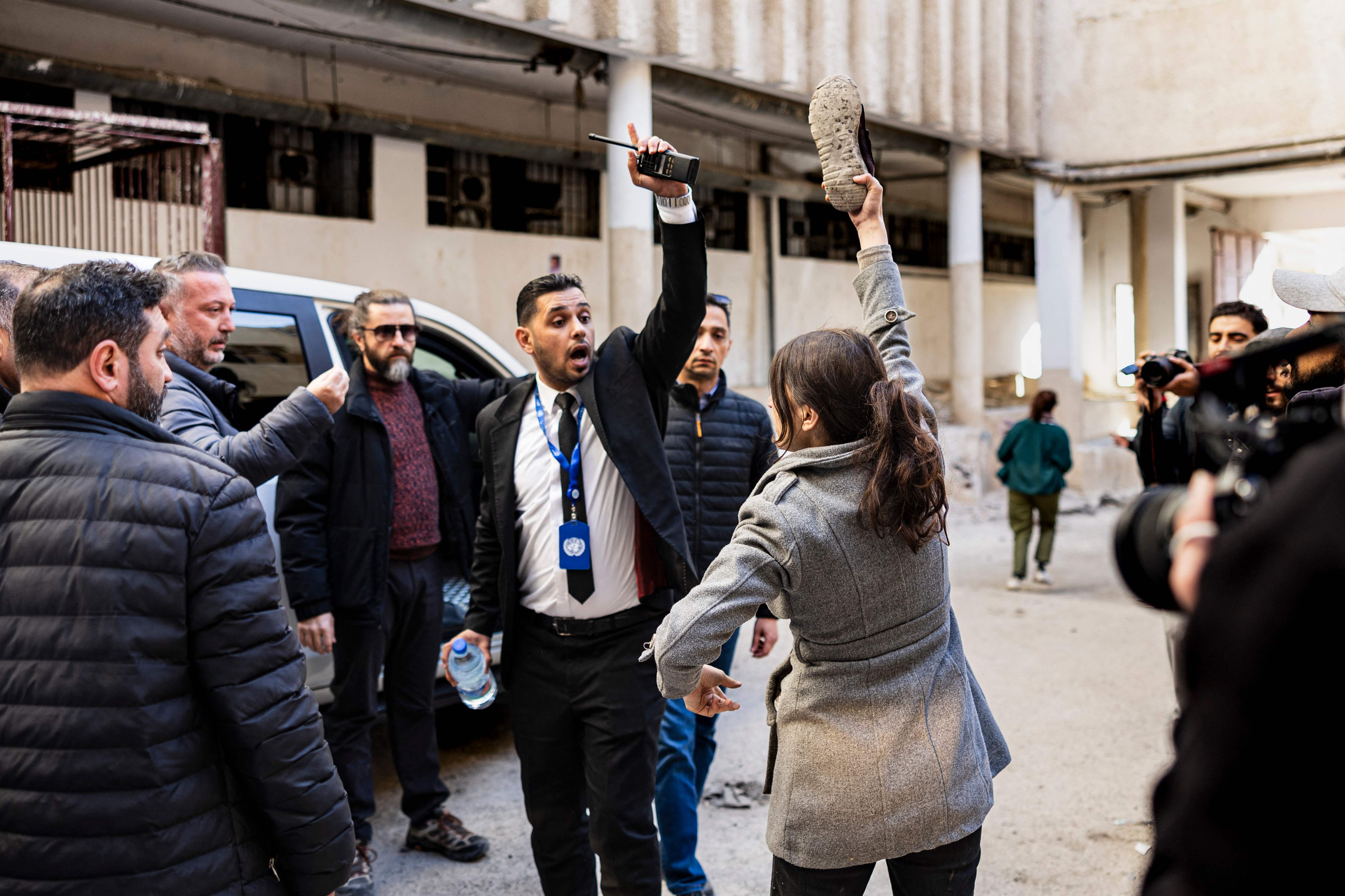 امرأة غاضبة تبحث عن شقيقها المفقود تلوح بحذاء أمام سيارة المبعوث الأممي خلال زيارة إلى سجن صيدنايا (أ ف ب)