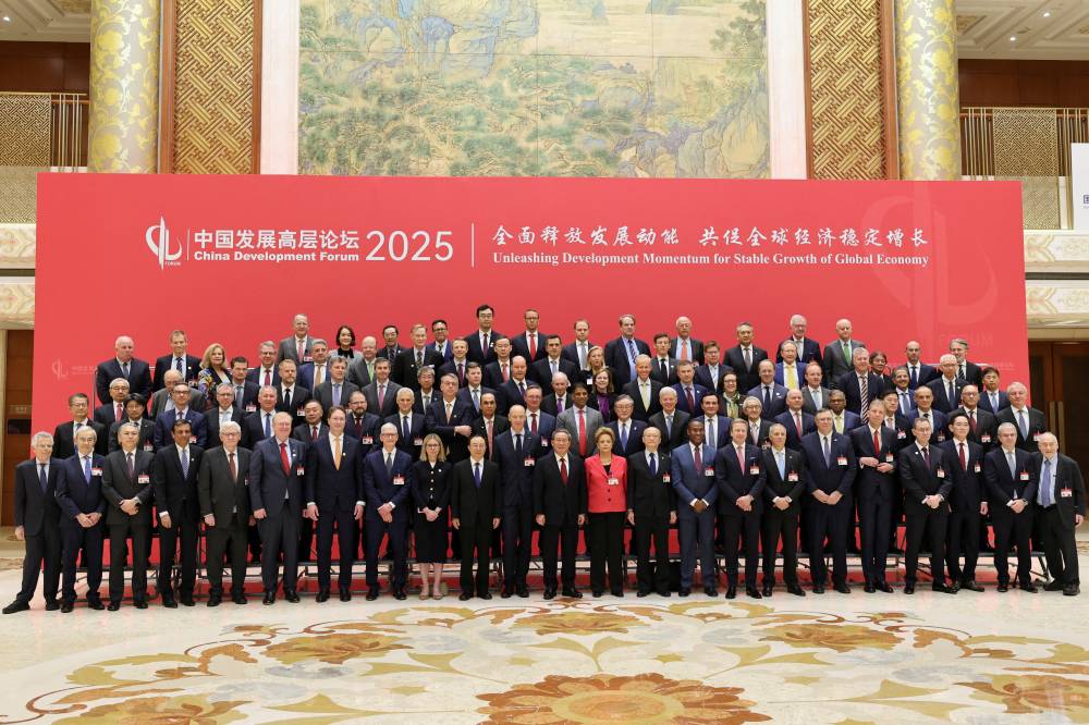 رئيس مجلس الدولة الصيني لي تشيانغ يلتقط صورة جماعية مع الحضور (رويترز)