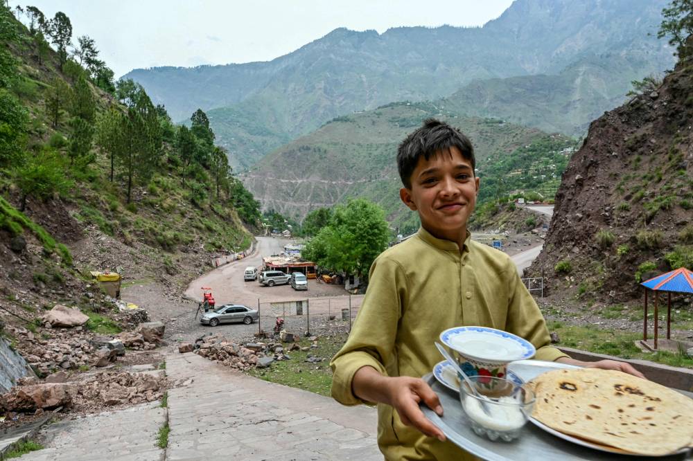 طفل يحمل الطعام في قرية بالقرب من مظفر أباد (أ ف ب)