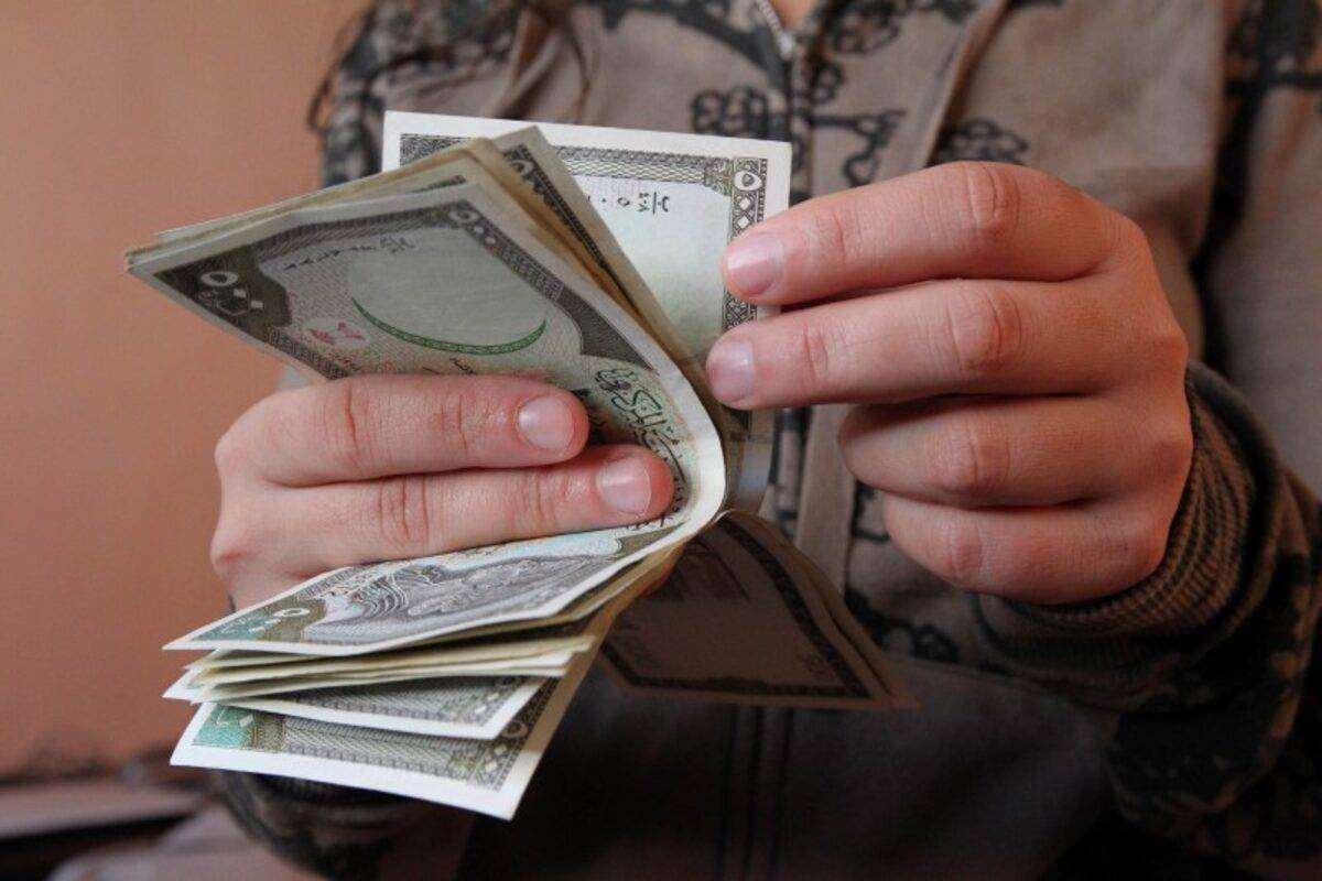 رجل يعد أوراقاً نقدية بالليرة السورية في دمشق (رويترز - أرشيفية)