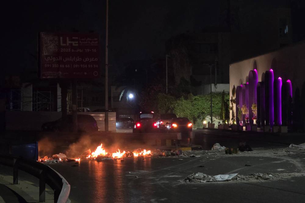  متظاهرون يشعلون إطارات، ويقطعون طريقًا رئيسيًا في طرابلس، مطالبين باستقالة الدبيبة (أ ف ب )