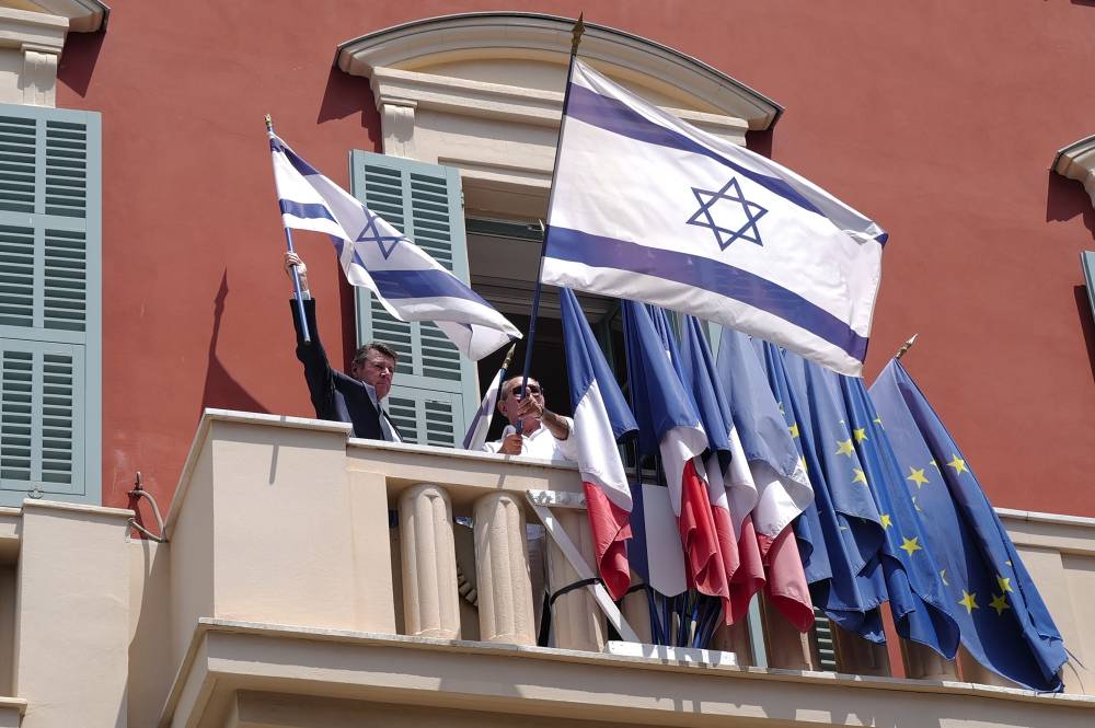 رئيس بلدية نيس كريستيان إستروسي ينزع الأعلام الإسرائيلية (أ.ف.ب)