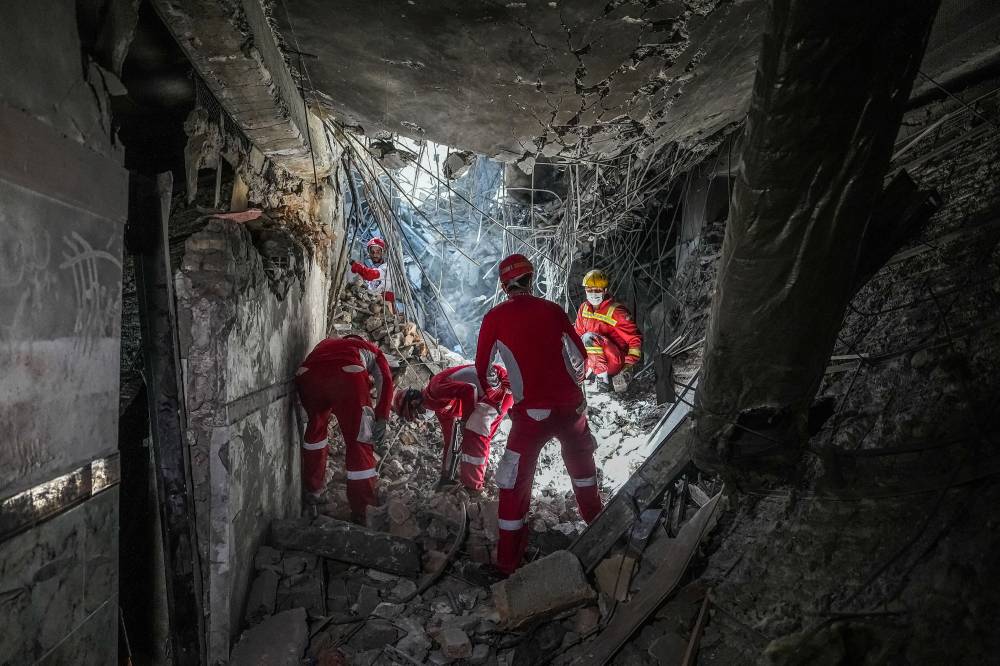 رجال إنقاذ ايرانيون بفحصون الأنقاض داخل مجمع سجن إيفين في طهران(أ ف ب ) 