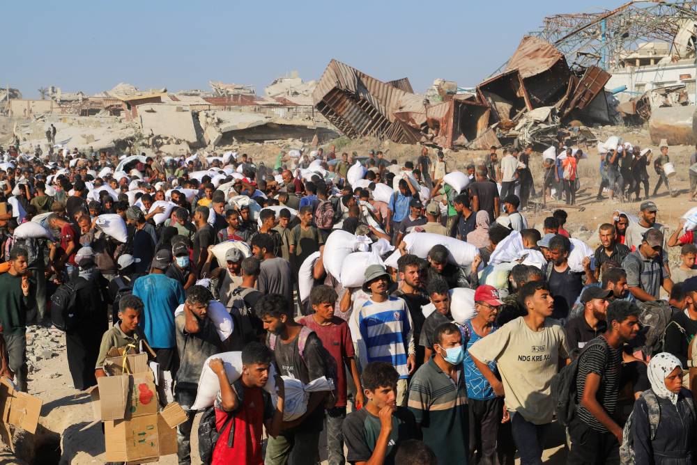  فلسطينيون يحاولون الحصول على أكياس طحين في بيت لاهيا حيث وصلت شاحنات تحمل مساعدات (رويترز)