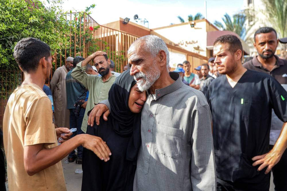 مشيعون خلال جنازات ضحايا القصف الإسرائيلي الليلي على مخيم للنازحين في منطقة المواصي (أ ف ب)