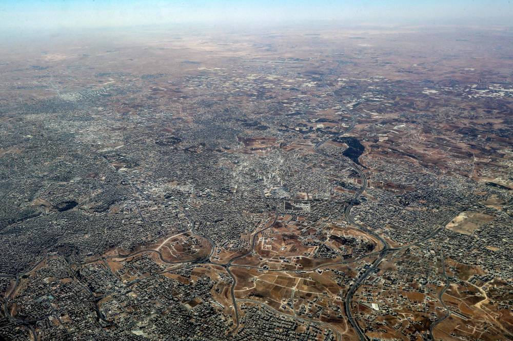 TOPSHOT - This aerial view shot from a German Air Force (Luftwaffe) military transport aircraft during an airdrop relief mission shows the scene in the Gaza Strip on August 5, 2025. Israel has been fighting Palestinian militant group Hamas in Gaza for 22 months and imposed a total blockade on March 2, partially lifted in May to allow a US-backed private agency to open food distribution centres. Aid convoys and airdrops by Arab and European militaries resumed last month, as UN-mandated expert reports warned famine was unfolding in the war-torn territory. (Photo by Khalil MAZRAAWI / AFP)