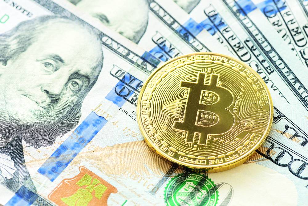 Gold Bitcoin on hundred dollars bills. Close-up, macro shot.