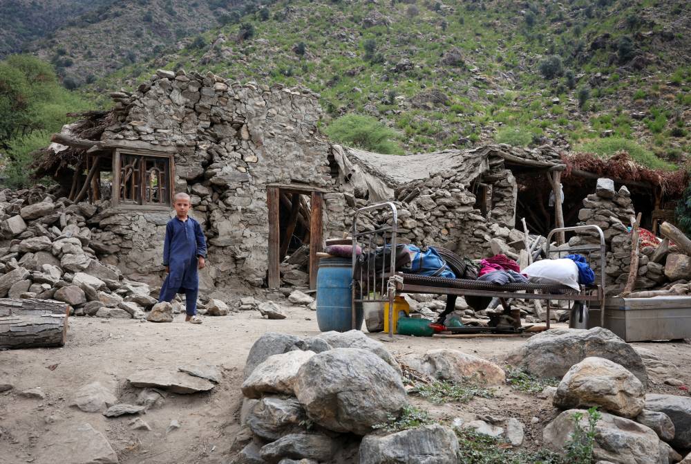 A boy stands in front of a house after a deadly magnitude-6 earthquake that struck Afghanistan on Sunday, at Lulam village, in Nurgal district, Kunar province, Afghanistan, September 3, 2025. REUTERS/Sayed Hassib