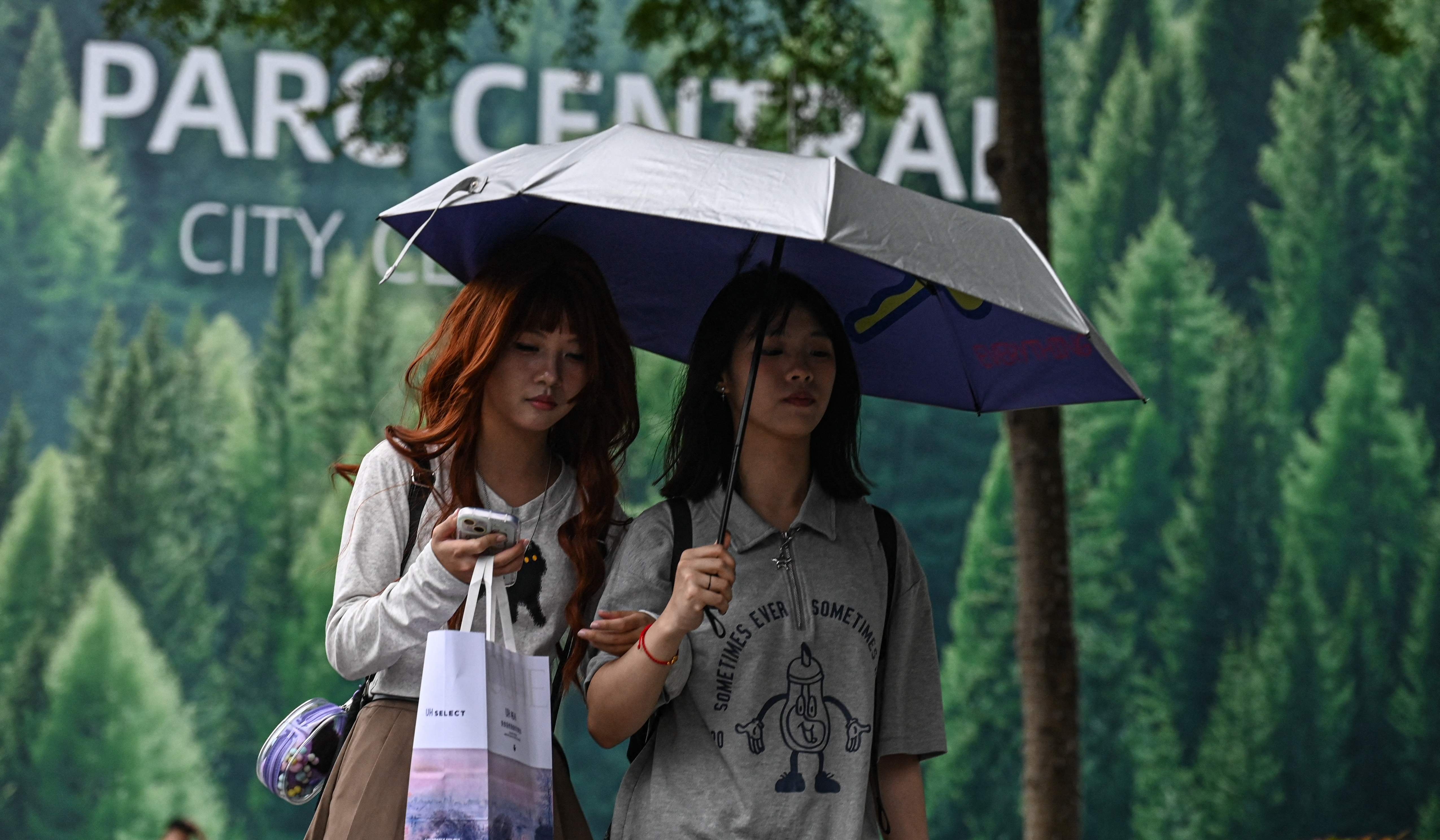 تحتميان بالمظلة من المطر في أحد شوارع غوانزو