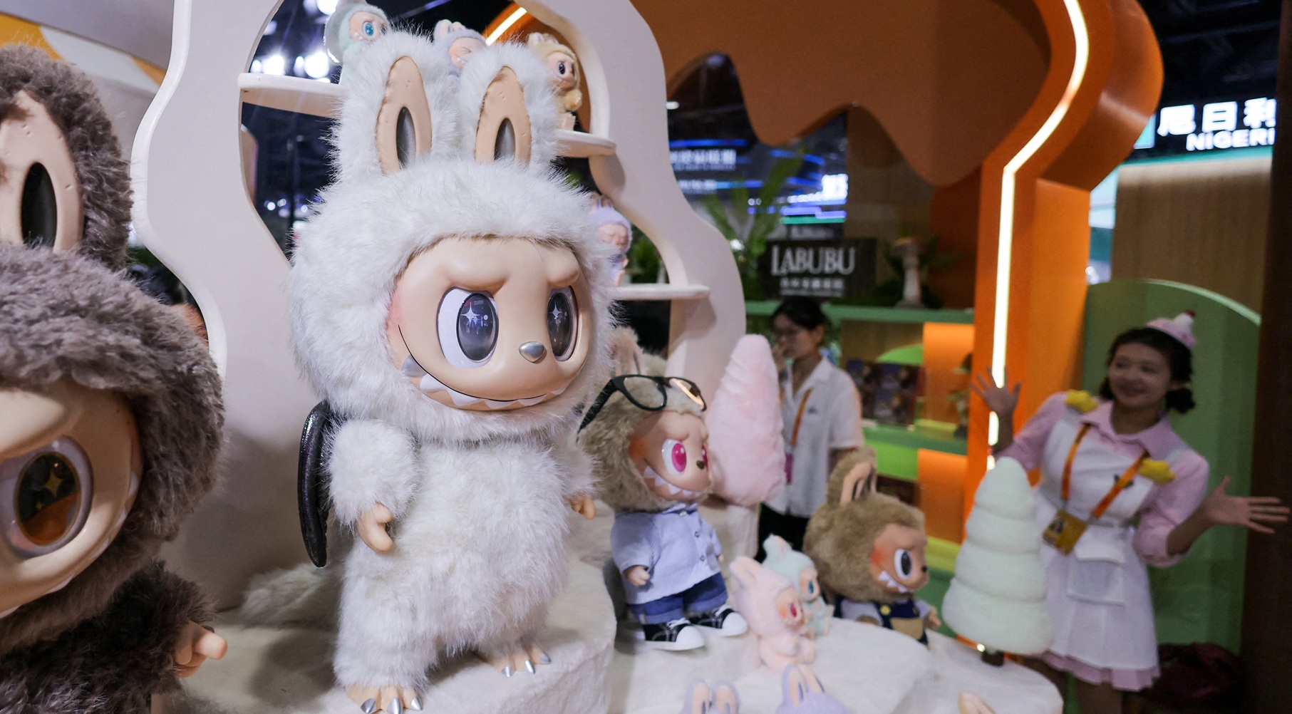 موظفة تشير إلى ألعاب لابوبو المعروضة في جناح بوب مارت في معرض الصين الدولي للتجارة في الخدمات (أرشيفية/رويترز)