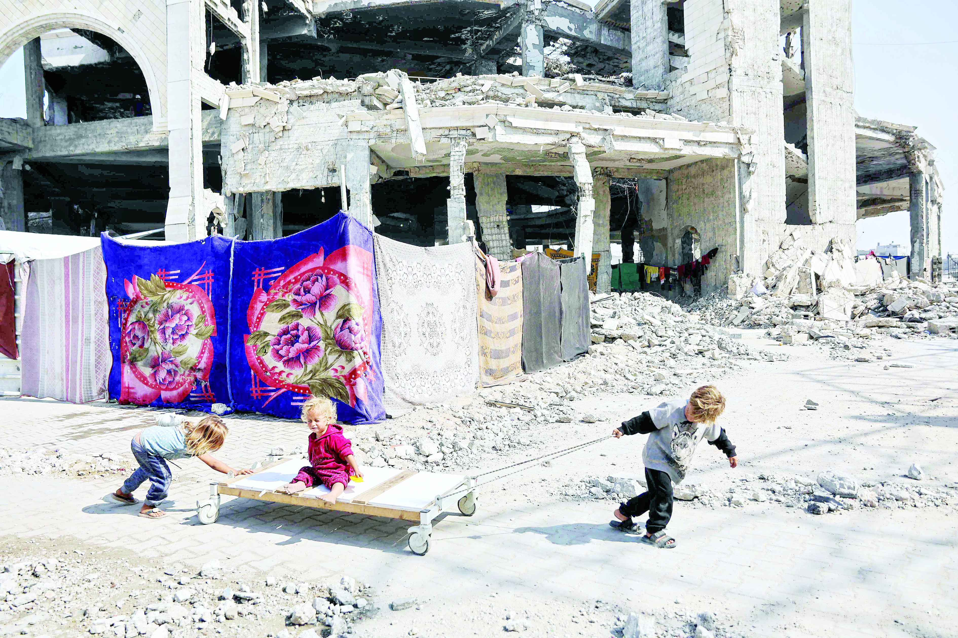 أطفال نازحون يلعبون خارج مسجد الإمام الشافعي المتضرر في حي الزيتون بمدينة غزة