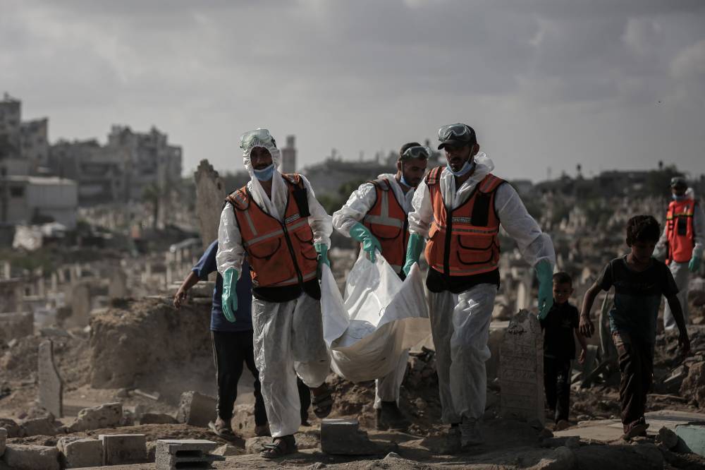 أفراد الدفاع المدني يحملون رفات ضحايا بمدينة غزة (بلومبرغ)