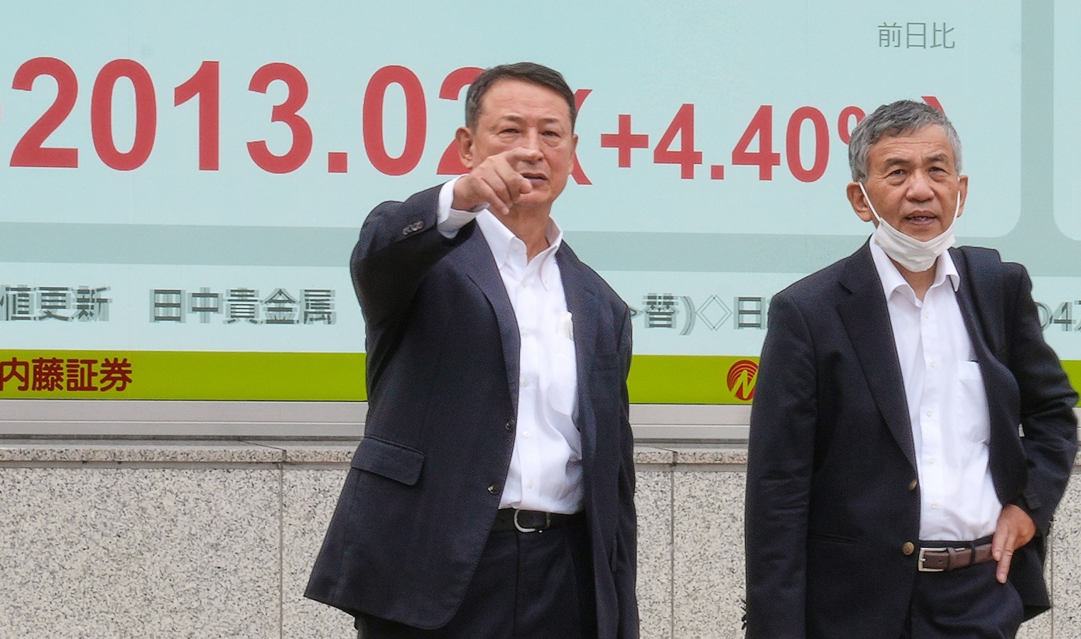 يقفان أمام شاشة تعرض تحركات أسواق المال في طوكيو