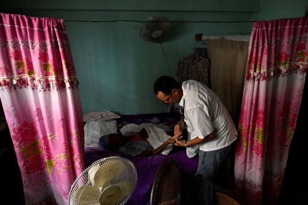 طبيب يفحص مريضة في منزلها مصابة بمرض ينقله البعوض (رويترز)