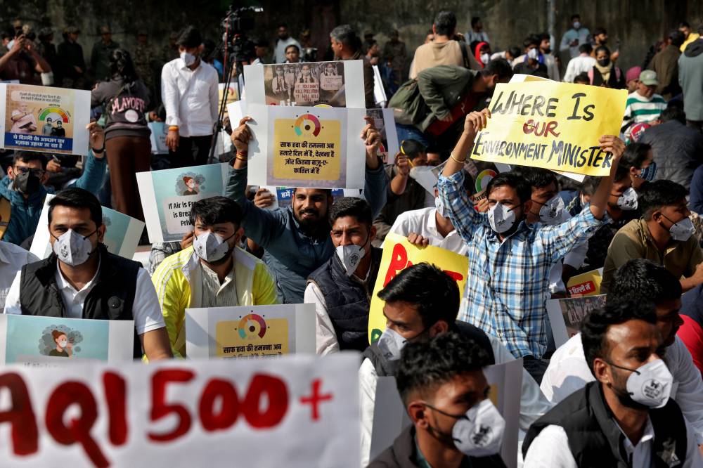 متظاهرون يحملون لافتات خلال احتجاج على تلوث الهواء في نيودلهي (رويترز)