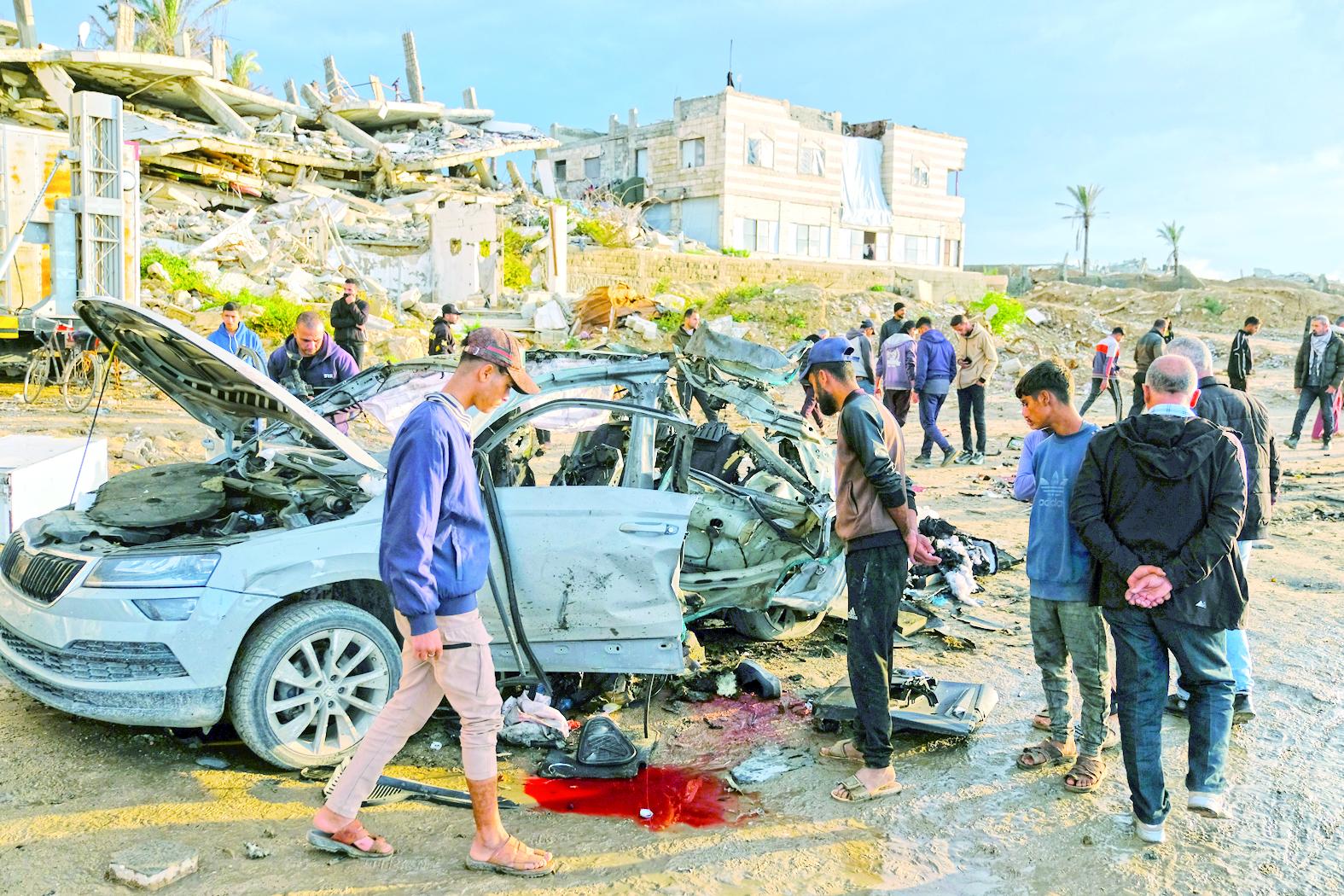 فلسطينيون حول السيارة المدمرة عقب الغارة الإسرائيلية في مدينة غزة 