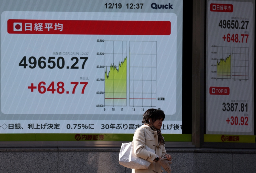 سيدة تمر أمام شاشة للمؤشر نيكاي في طوكيو