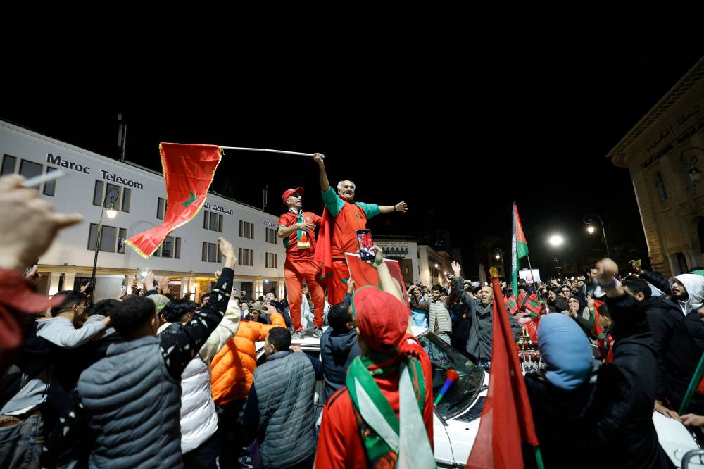 Moroccans celebrate in Rabat following their team's victory in the FIFA Arab Cup 2025 final football match between Jordan and Morocco that took place at the Lusail Stadium, in Lusail on December 18, 2025. (Photo by Abdel Majid BZIOUAT / AFP)