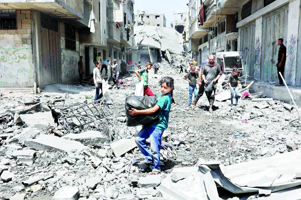 فلسطينيون ينقذون أغراضاً من أنقاض منازل دُمّرت جراء غارات إسرائيلية على حي الزيتون الجنوبي بمدينة غزة (أ رشيفية)