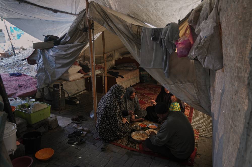   عائلة فلسطينية تتناول الطعام داخل خيمتها في مخيم الشاطئ،(ا ب)