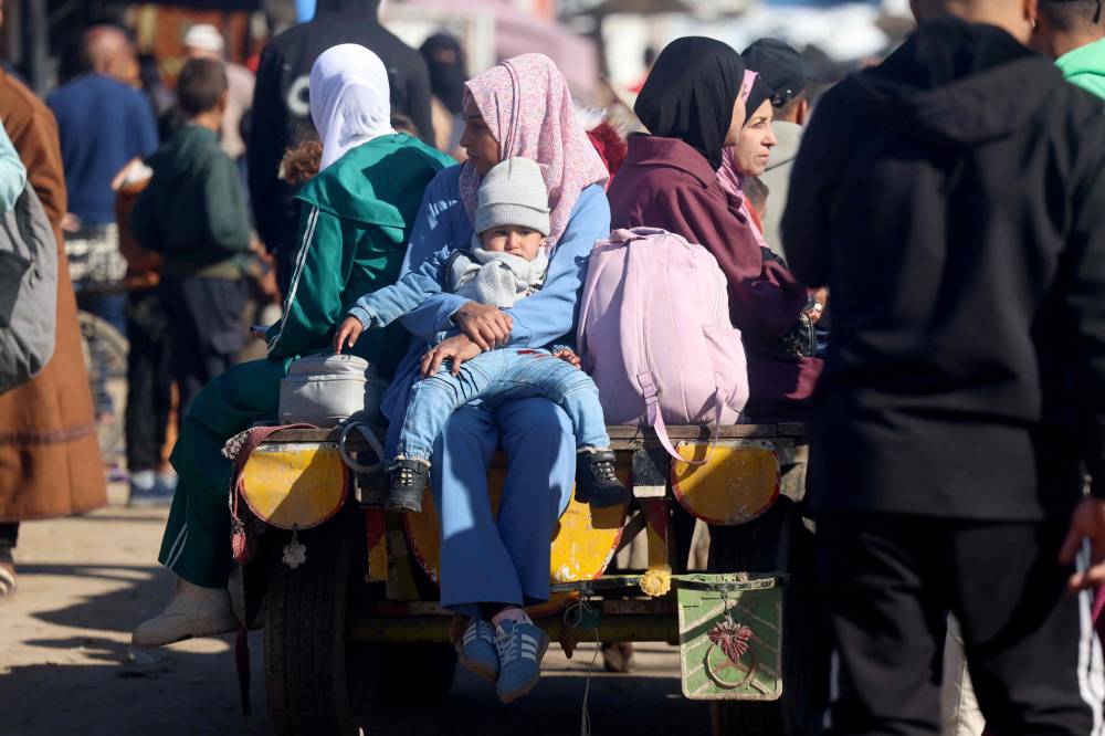   نازحة تحمل طفلها الرضيع وهي تركب عربة في مخيم خان يونس (ا ف ب) 