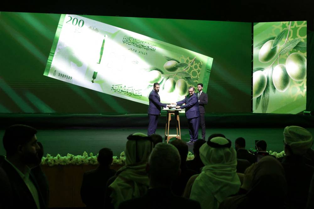 الشرع والحصرية خلال إطلاق العملة السورية الجديدة (أ ف ب) 