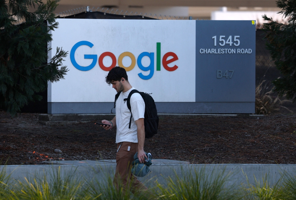 شاب يمر بجوار لافتة أمام مقر غوغل في ماونتن فيو، كاليفورنيا