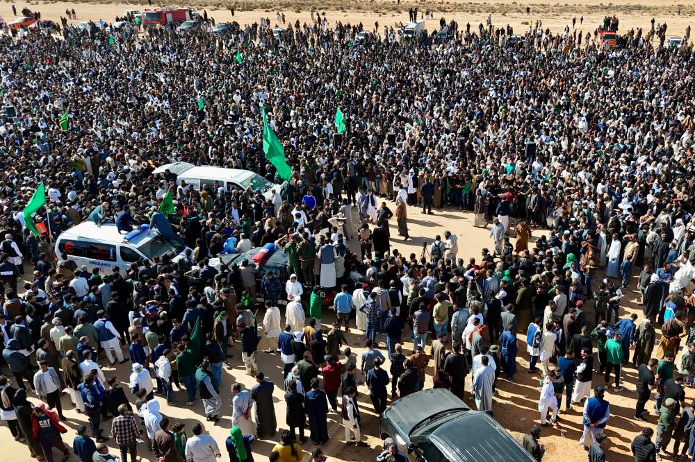 
 الليبيون يحتشدون لحضور جنازة سيف الإسلام، وهم يحملون صورة والده في مدينة بني وليد(أ ب )