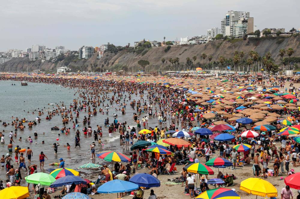  زوار يستمتعون بقضاء وقتهم على أحد أشهر شواطئ ليما وهو شاطئ أغوا دولسي في تشوريلوس (أ.ف.ب) 