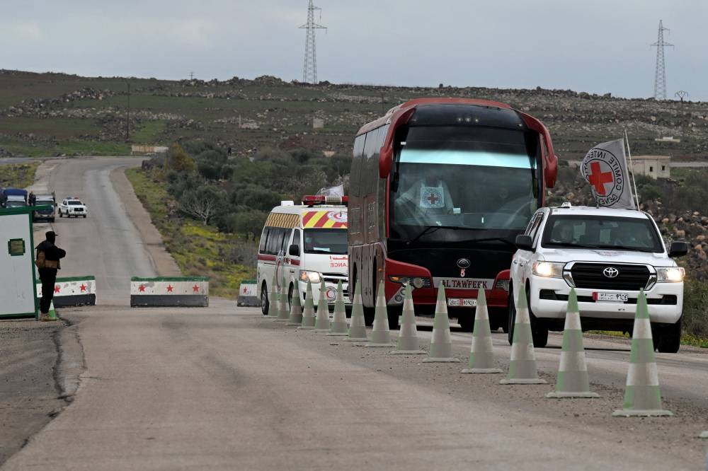  باص يحمل معتقلين يصل إلى نقطة التبادل عند مدينة السويداء (أ.ف.ب)