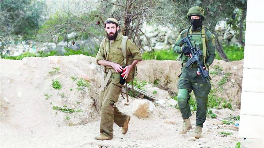 مستوطن إسرائيلي بمعية جندي في الضفة الغربية (ارشيفية)