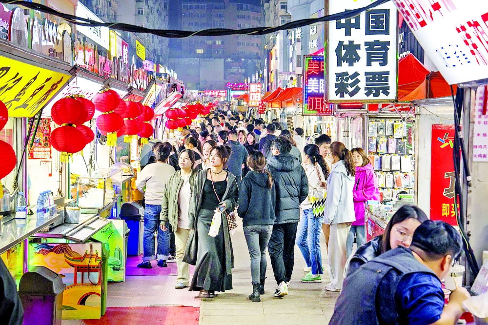 مارة في شارع مليء بأكشاك الطعام في سوق تايدونغ الليلي بمدينة تشينغداو الصينية (أرشيفية)