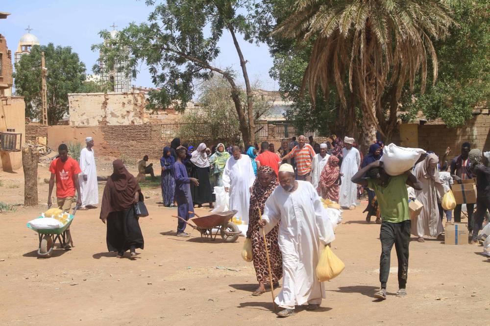 سكان يتلقون مساعدات في أم درمان في خضم الحرب الأهلية الدائرة في السودان (أ ف ب)