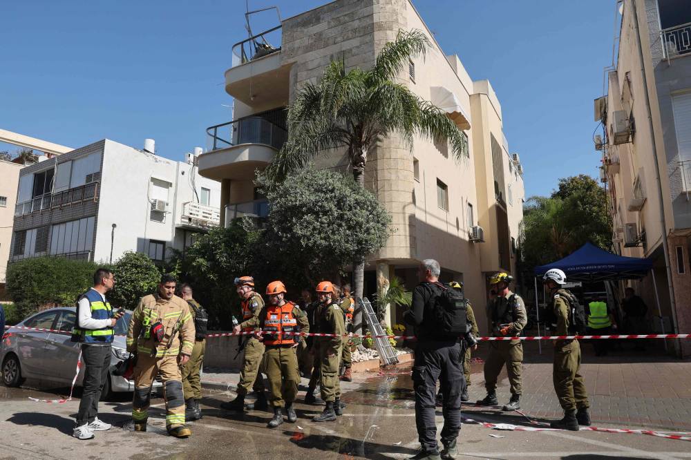 عناصر إطفاء إسرائيليون يطوقون منطقة متضررة جراء قصف (أ ف ب)