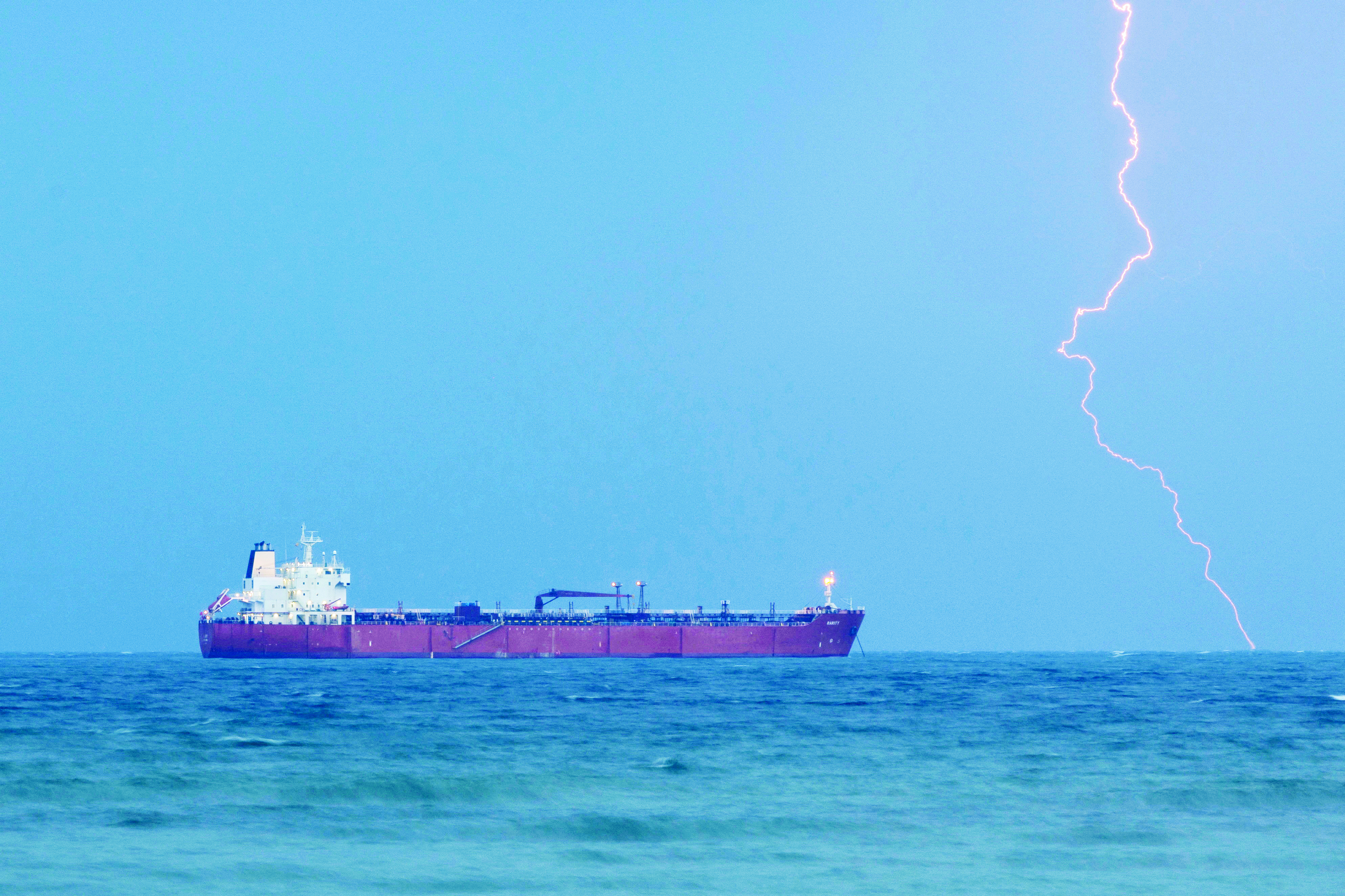 ناقلة نفط ترسو في ميناء مسقط وسط وميض البرق في الأفق