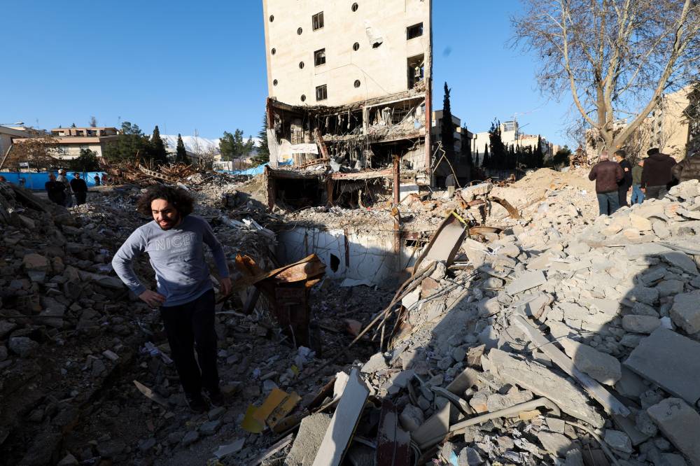 رجل يقف وسط الأنقاض المتبقية من مبنى دُمر جراء غارة جوية في طهران (رويترز)