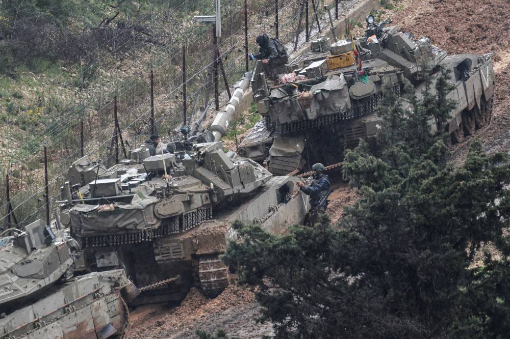  جنود إسرائيليون يعملون على تحريك دبابات غرزت في الوحل على الحدود اللبنانية (رويترز)