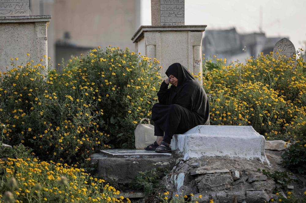  فلسطينية تزور أقاربها الراحلين في مقبرة السرايا في مدينة غزة(أ.ف.ب)