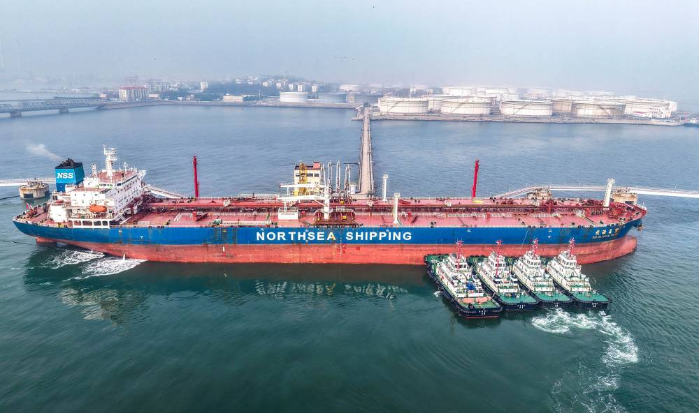 قاطرات تقوم  بنقل ناقلة نفط خام إلى رصيفها في محطة النفط بميناء تشينغداو، بمقاطعة شاندونغ شرقي الصين