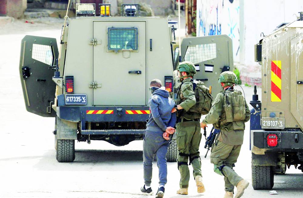 جنود إسرائيليون يعتقلون شاباً أثناء مداهمة مخيم عسكر شرقي نابلس (أرشيفية)